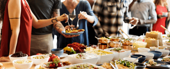 A group of people gathered around a buffet table, serving food and sharing a meal together.